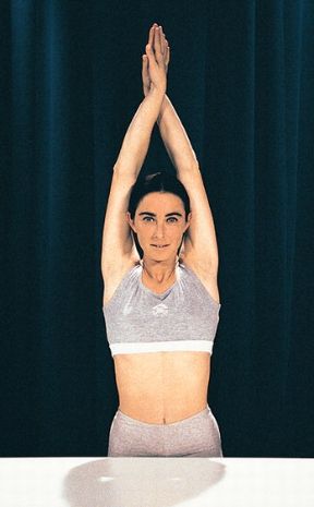 Esercizio per gli arti superiori. Movimenti per gli arti superiori da eseguire in piedi. Sollevamento delle braccia con mani incrociate. 